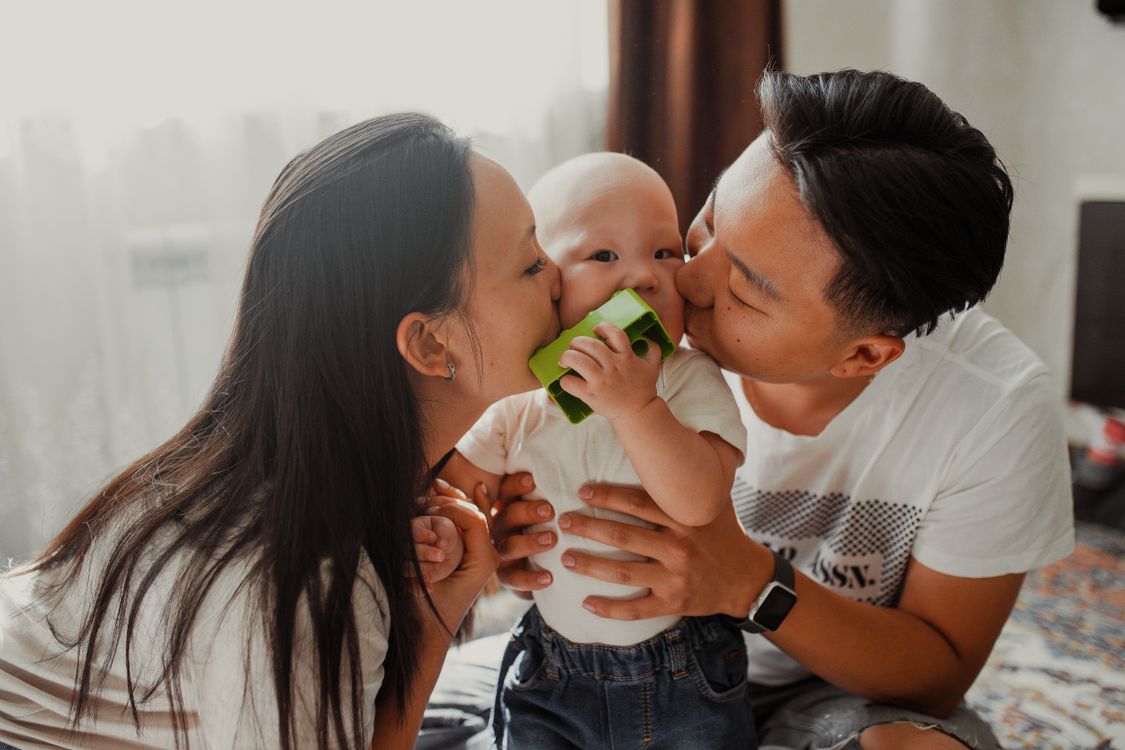 Eltern küssen liebevoll ihr Baby, ein enger Familienmoment