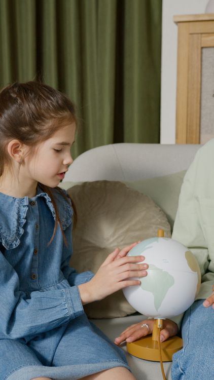 Ein Mädchen betrachtet einen Globus auf dem Sofa zu Hause