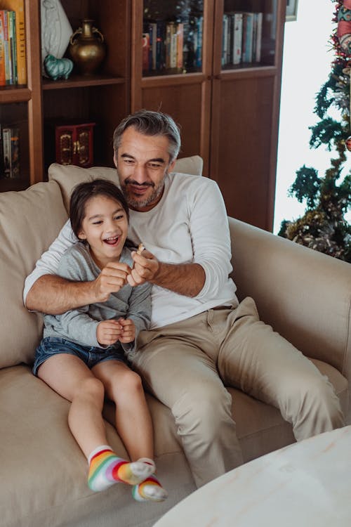 Vater und Tochter spielen gemeinsam auf dem Sofa