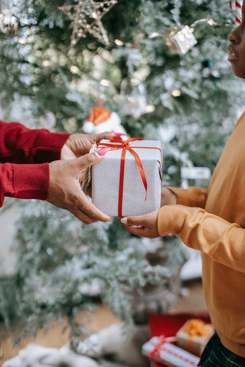 Ein Kind bekommt ein Geschenk von einer Erwachsenen uberreicht