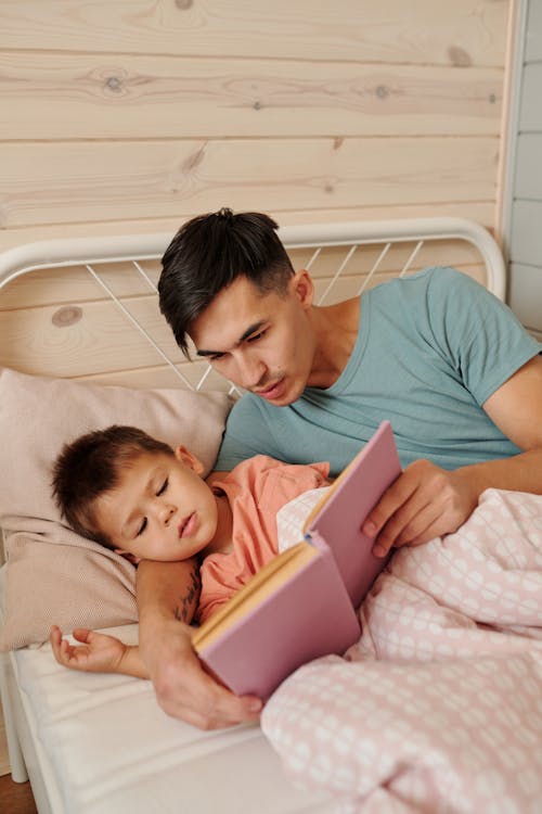 Vater liest seinem Kind im Bett ein personalisiertes Buch vor
