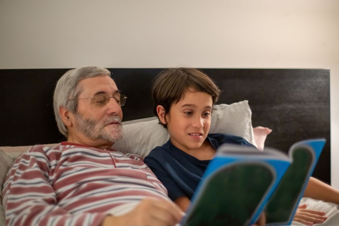 Opa und Enkelin schauen gemeinsam in ein Buch