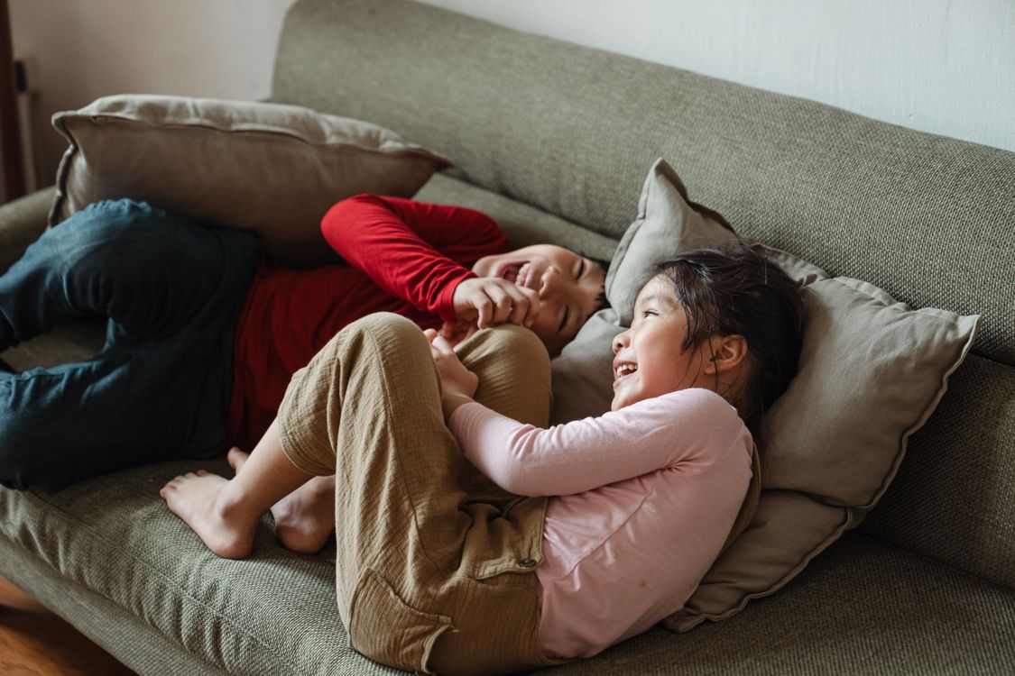 Zwei Kinder spielen zusammen und lachen auf einem Sofa