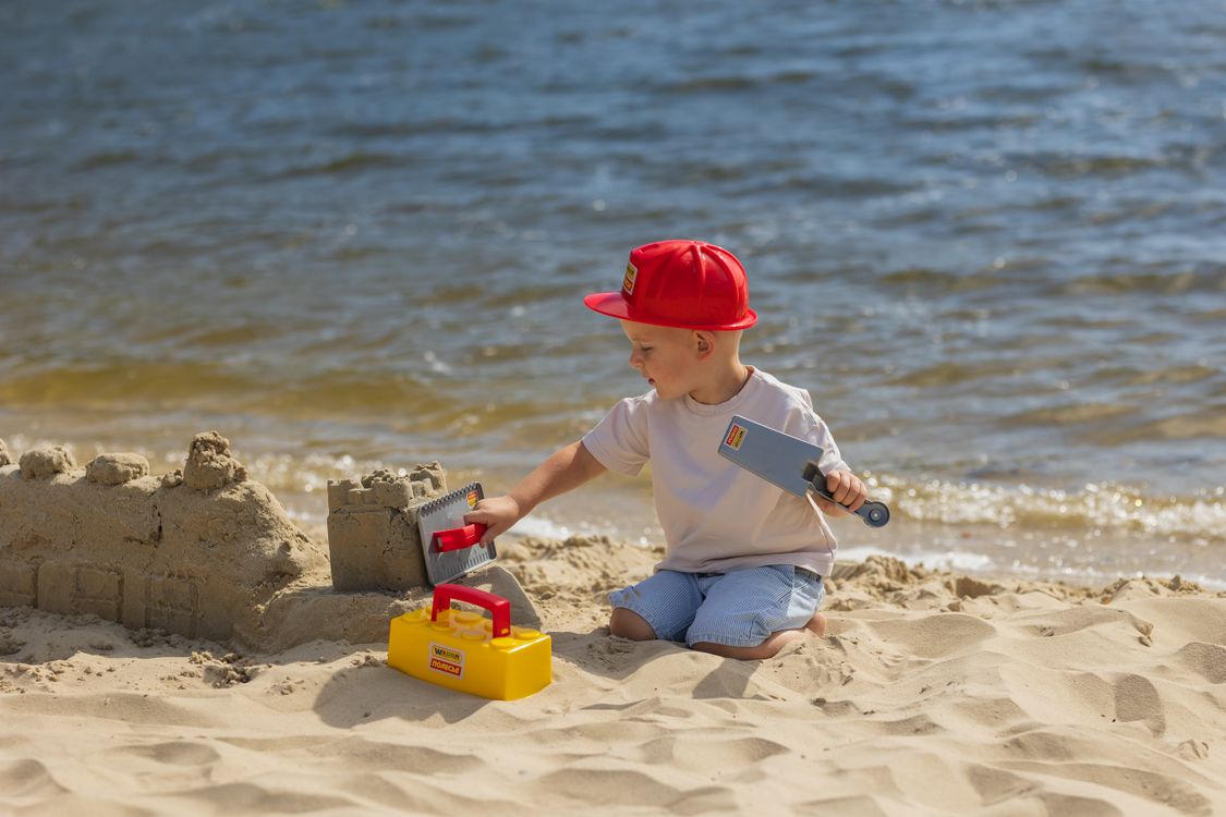 Junge baut eine Sandburg am Strand, eine typische Urlaubserinnerung für spätere Gespräche