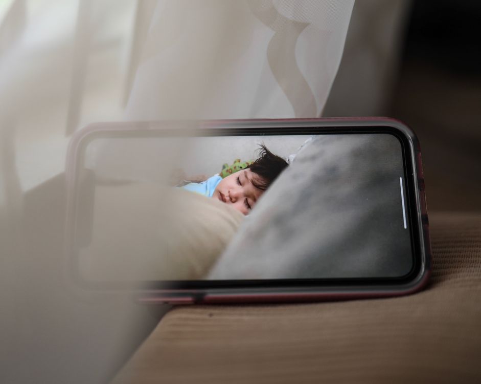 Smartphone-Bildschirm zeigt ein schlafendes Kind über eine Babyfon-Kamera