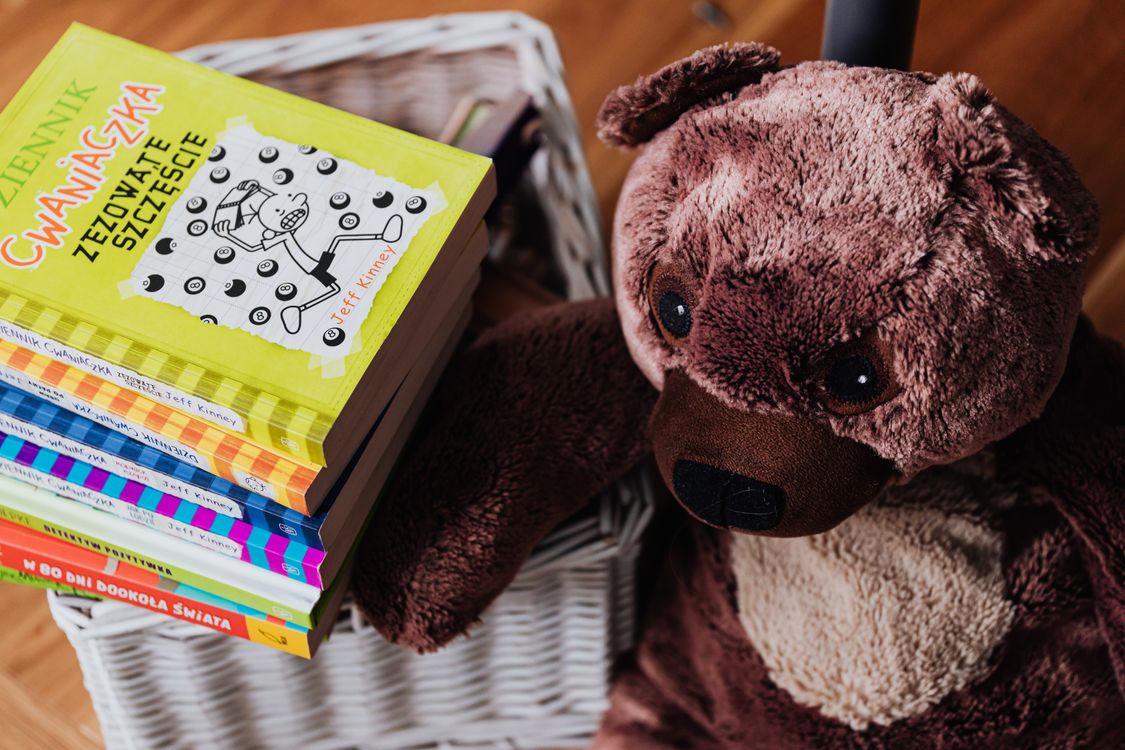 Stapel bunter Bilderbücher neben einem Teddybär in einem Kinderzimmer