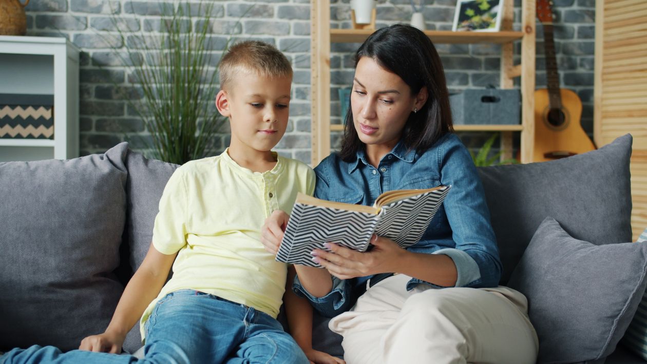 Mutter und Kind lesen gemeinsam ein Buch auf dem Sofa